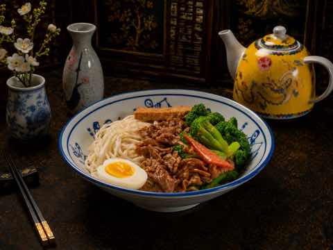 牛肉麵配西蘭花、滷蛋與青菜，盛於青花碗中