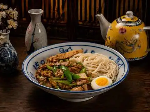 Braised pork noodle bowl with a halved soft egg and greens