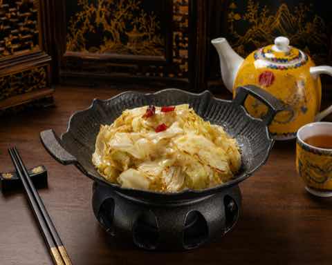 手撕包菜與紅辣椒同燒，盛於深色鑄鐵鍋