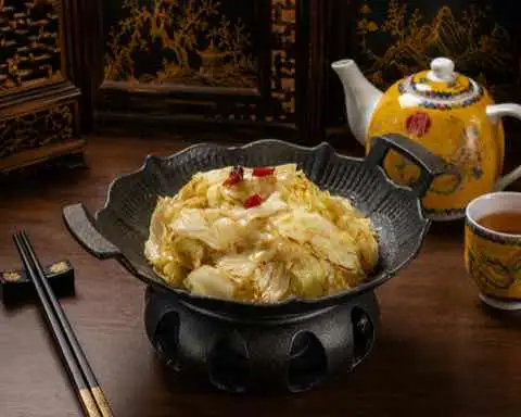 Braised cabbage with red chili in a dark cast iron pot