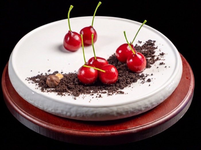 Fresh cherries with dark crumb arranged on a white plate