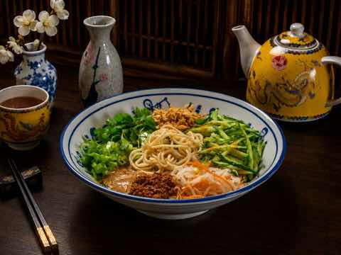 麵條浸在芝麻湯底中，配蔥花、黃瓜與酥料