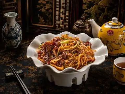 Fried rice noodles with beef and bean sprouts in a scalloped bowl