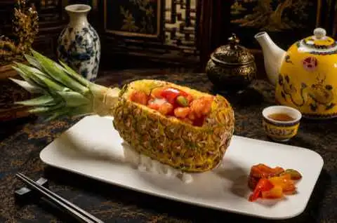 Fried rice served in a hollowed pineapple half on a white plate