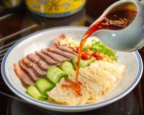 香氣醬汁現場淋在切片肉與黃瓜組成的涼盤上