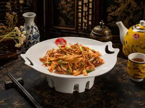 Shredded mushrooms tossed with chili in a white lotus-shaped dish