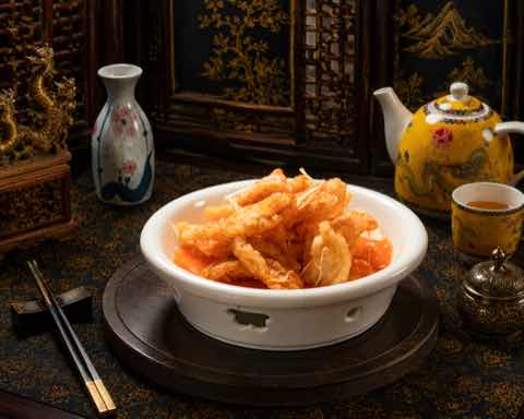 酥炸裹粉豬肉裹上糖醋醬，盛於白碗