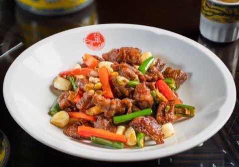 牛肉片與甜椒、蒜同炒,裹上深色醬汁