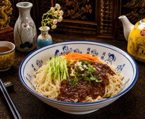 炸醬麵鋪上深色肉醬、黃瓜絲與紅蘿蔔絲